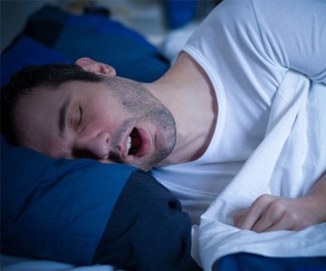 Man in white shirt sleeping and snoring in bed