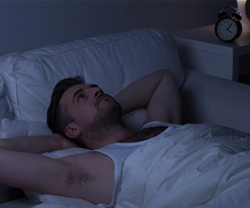 Man with sleep apnea lying awake in bed at night