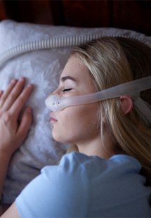 A young woman sleeping with a CPAP machine