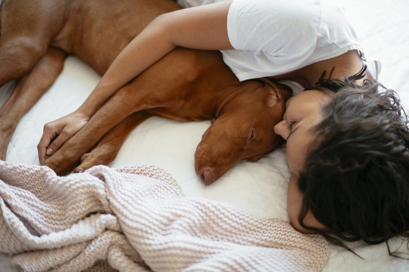 young woman sharing bed with dog