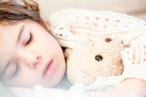 Sleeping child hugging a stuffed bear