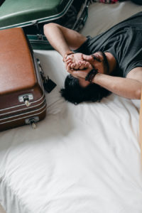 Man laying on bed with suitcases