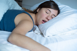 Woman with sleep apnea snoring in bed