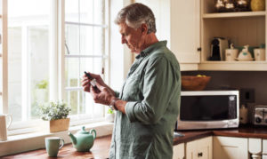 Man in kitchen reading CBD bottle