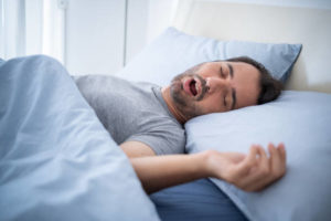 Snoring man sleeping in a bed