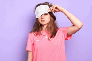 Woman lifting a sleep mask off her face on purple background