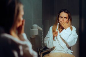 Concerned woman covering her mouth while holding her toothbrush 